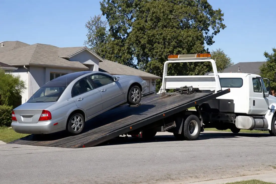 Free pickup: flatbed tow truck loading a sedan at a home in the U.S.